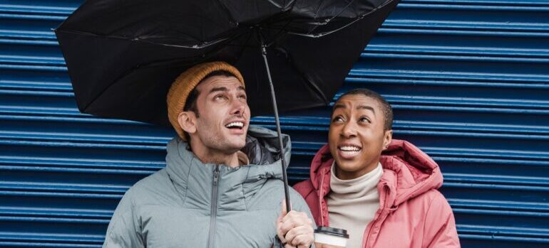 A cuple struggling to hold on totheir umbrella due to wind.