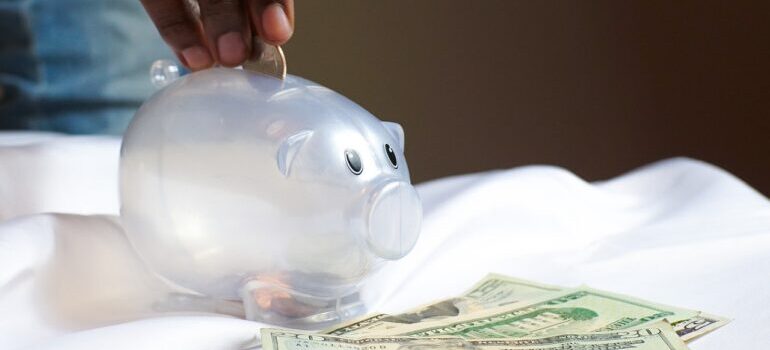 A man putting a coin into transparent piggy bank