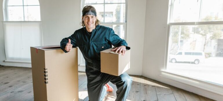 A smiling movers holding a box and giving thumbs up for long distance moving companies Provo.