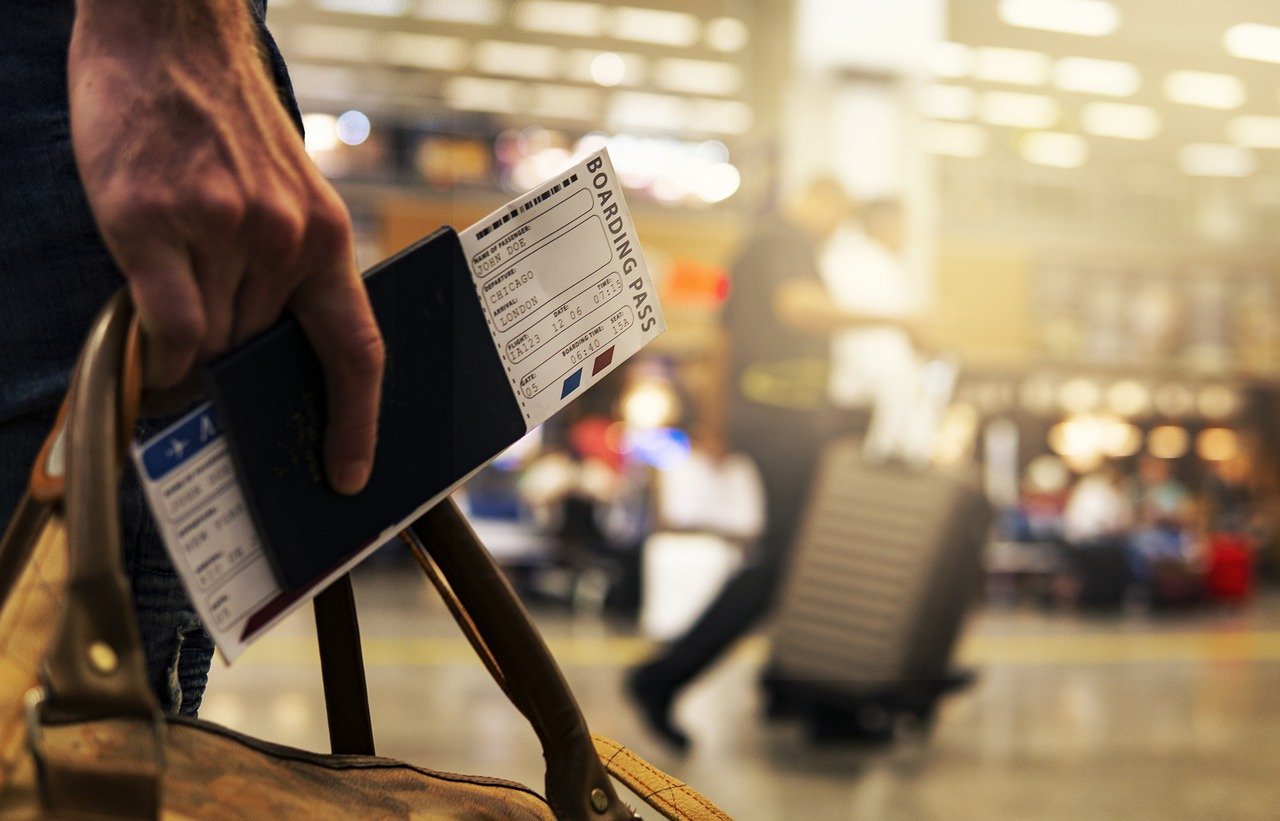 A man holding a bag and a plain ticket on an airport