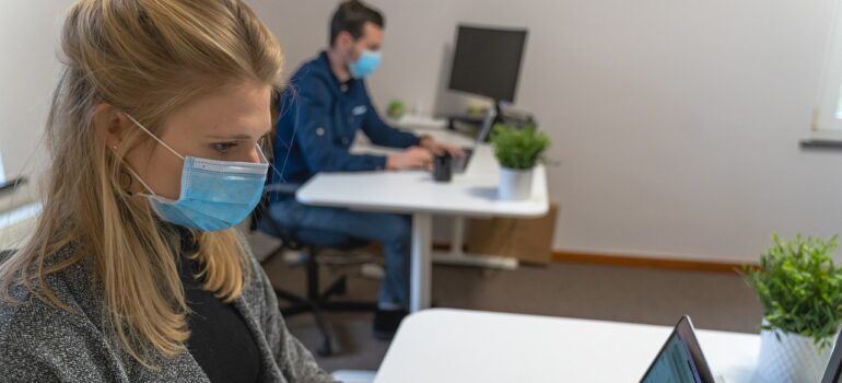 A man and a woman working in an office with face masks.