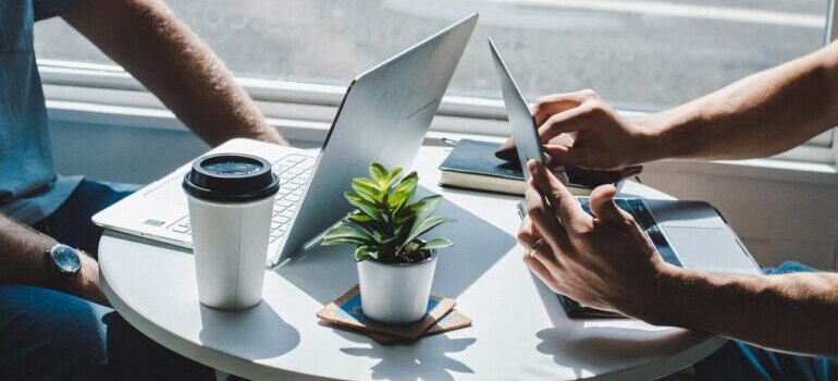 Two people sitting at a table with laptops.