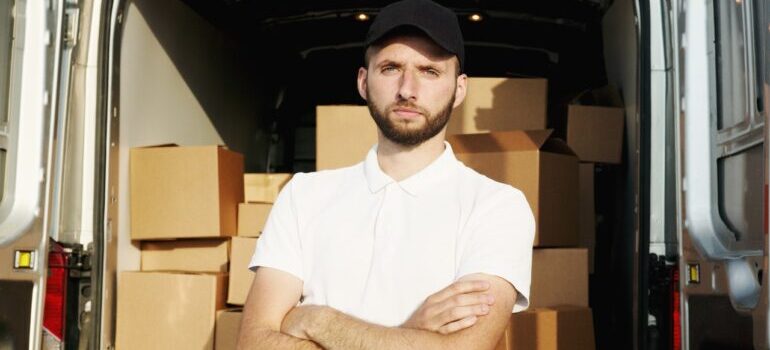 A mover posing proudly behind a moving van.