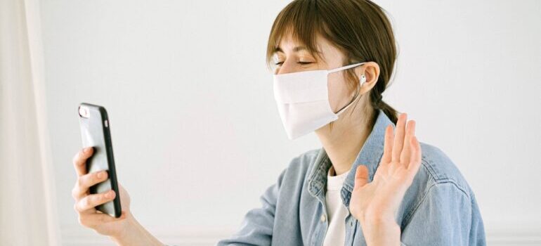 A young woman wearing a mask and videochatting.