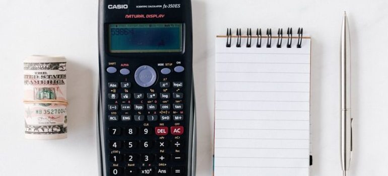 calculator, notepad, money, and a pen, representing what you will need for moving during Christmas
