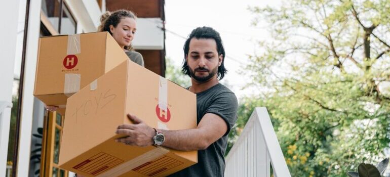 A young couple carrying moving boxes.