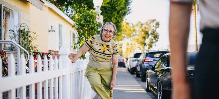 AN old lady smiling in front of her house.