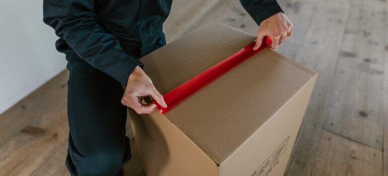 A mover sealing a moving box.