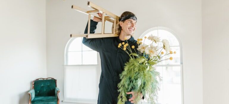 One of the top movers in San Jose holding a chair and a plant.