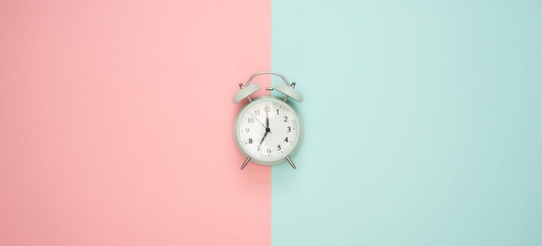 A clock on a blue and pink surface. 