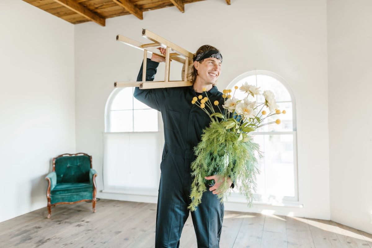 A mover holding a plant and a chair.