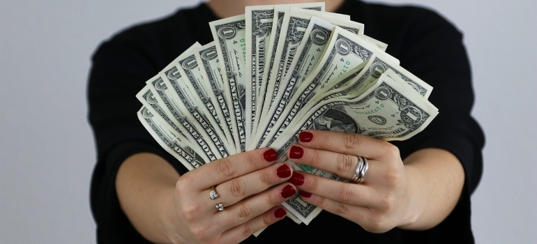 A woman holding money with which to pay for the top movers in Boston.