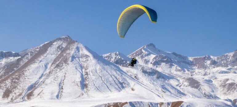 Person in yello parachute over snow-covered mountain