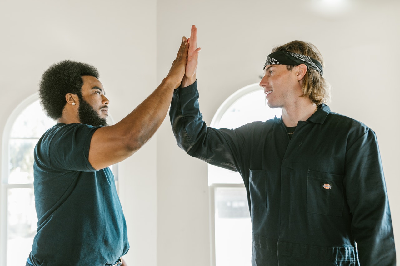 Two movers high-fiving after improving their performance due to following essential practice guidelines for moving companies.