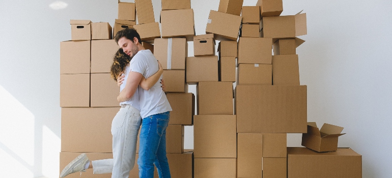 two people hugging in front of moving boxes