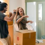 A happy couple dancing and having fun during packing because they managed to get discounts when moving.