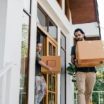 A couple carrying moving boxes.