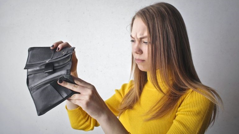 A woman frowning at an empty wallet.
