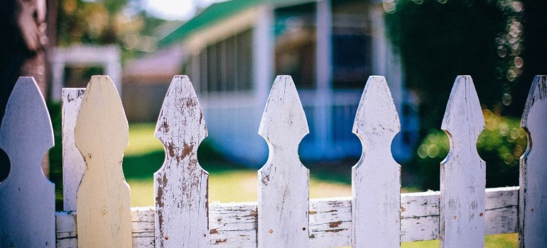 A white picket fence and a house behind it.