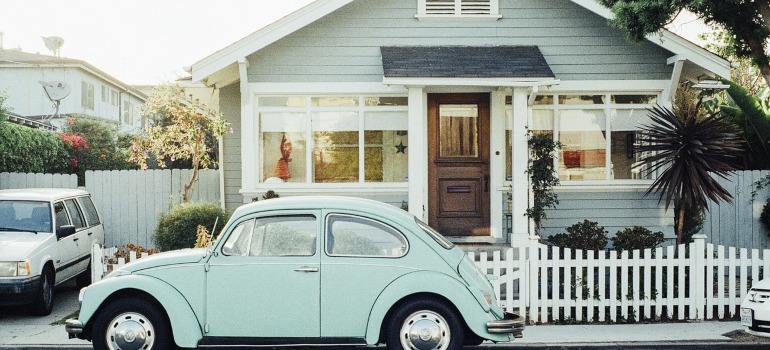 A mint car in front of a house.