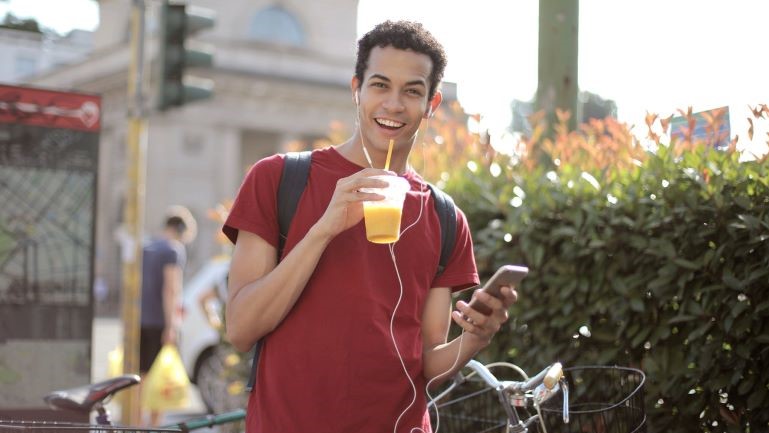 A young man smiling and having a drink.