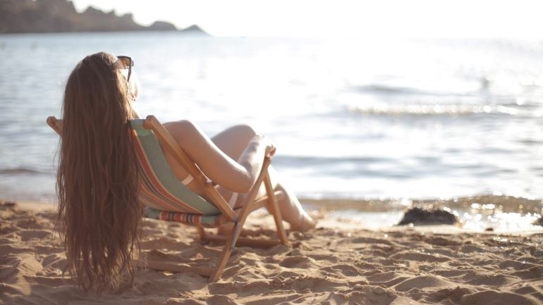 A woman sun tanning at the beach.