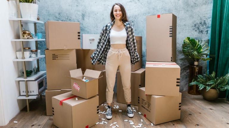 A woman standing among moving boxes.