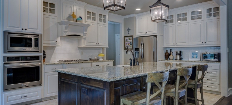 a kitchen with a cupboard, microwave oven and chairs