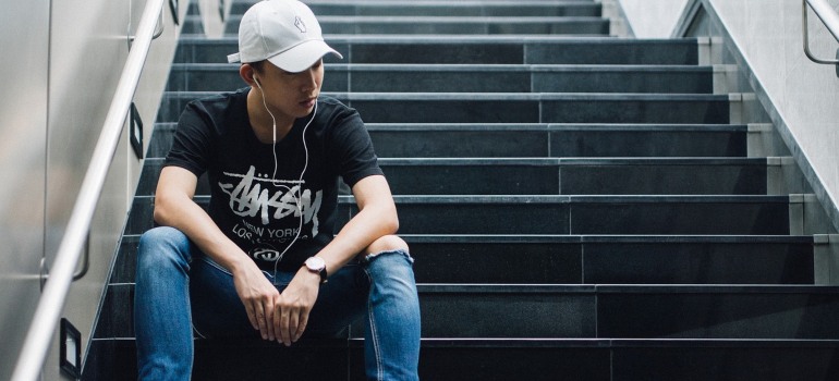 a boy sitting on stairs, listening to music on his earphones