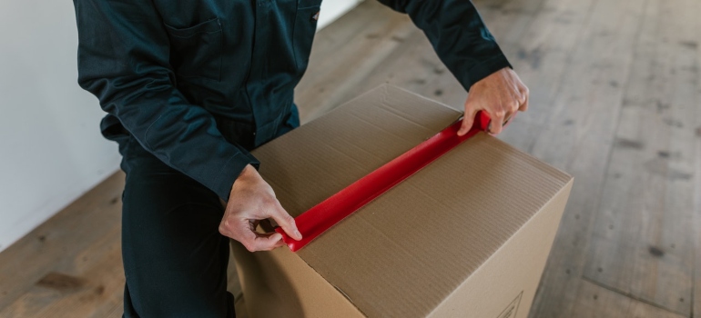 A person sealing a moving box 