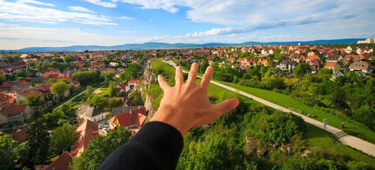 A person's hand and the view of a city behind it.
