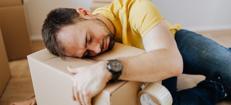 a tired man sleeping on a carton box.