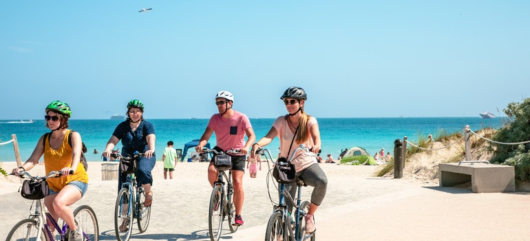People riding a bike on the beach after moving from Los Angeles to Miami