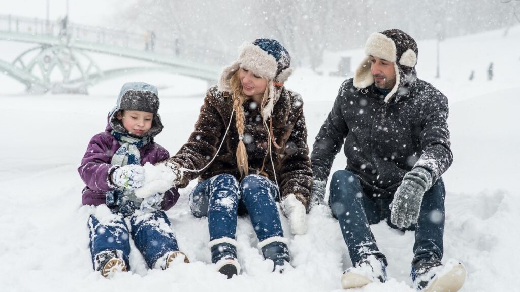 a couple with a child sitting in the snow