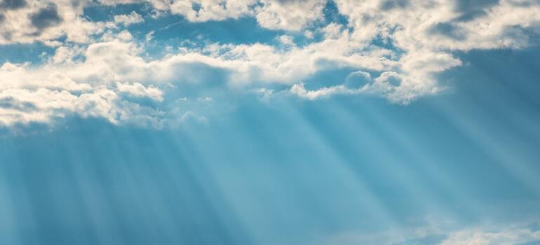 A sky with sun rays and some white clouds