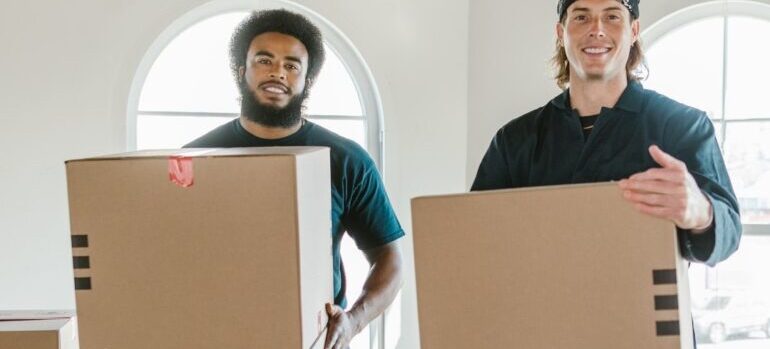 two men of the cross country moving companies Medford holding boxesc while standing next to each other