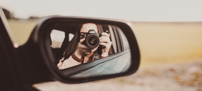 a woman, who's moving with the help of long distance moving companies Canton, taking a picture of herself in the rearview mirror