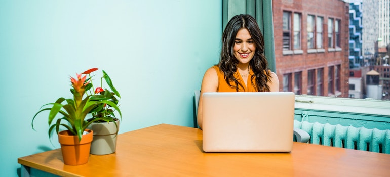 A woman using a laptop in a room with blue walls.