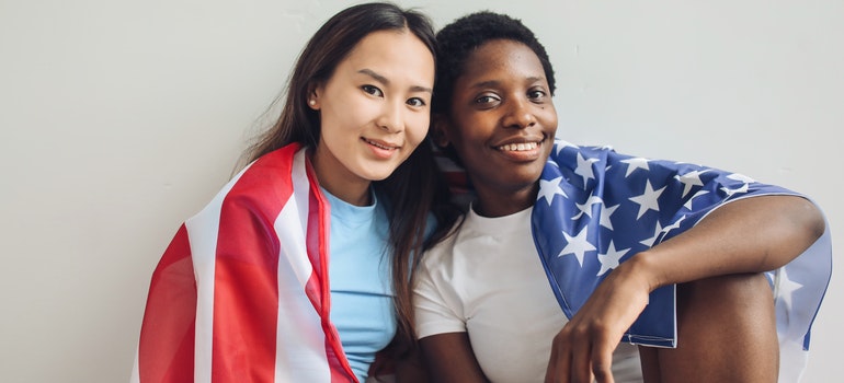 Two women sitting with the American flag around them.