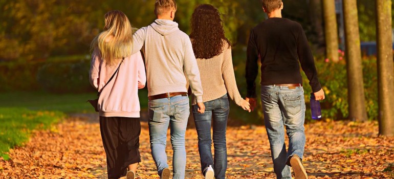 Two couples walking in a park during fall.