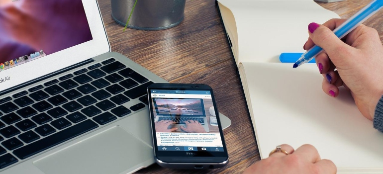 a laptop, phone, and a notebook