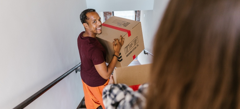 smiling gay carrying cardboard box