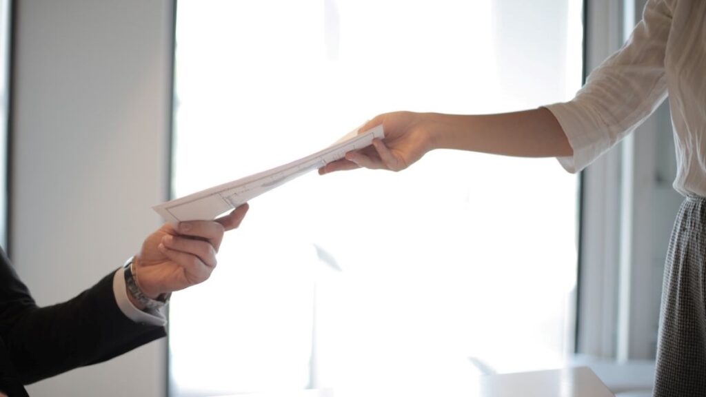 An employee handing over paperwork to a colleage.