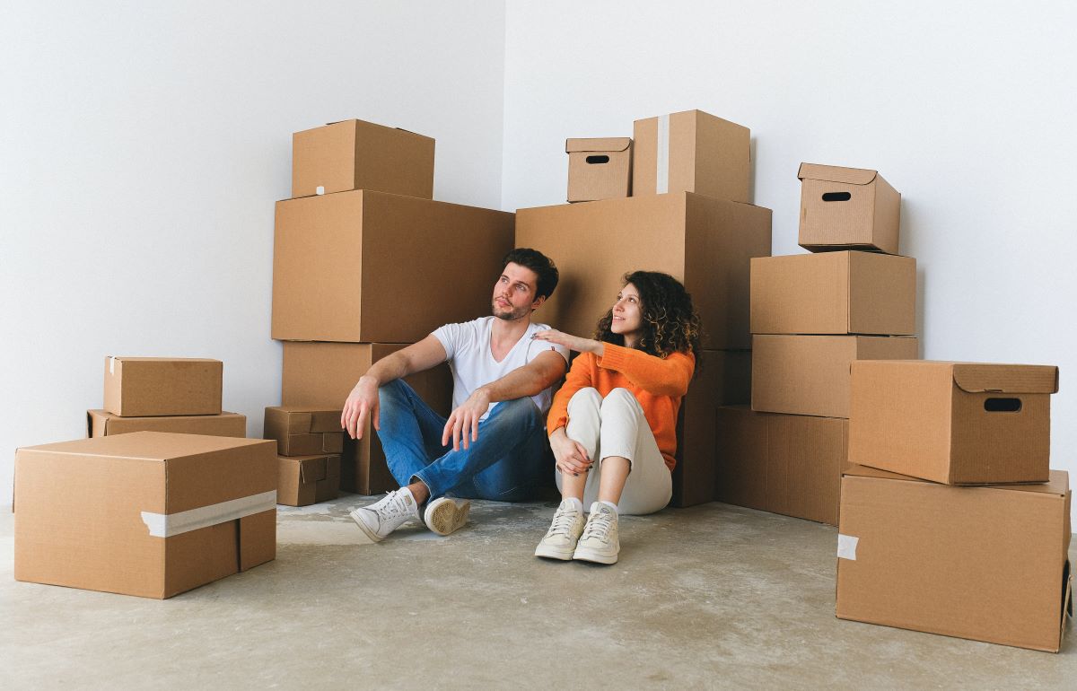 A couple sitting on the floor among moving boxes.