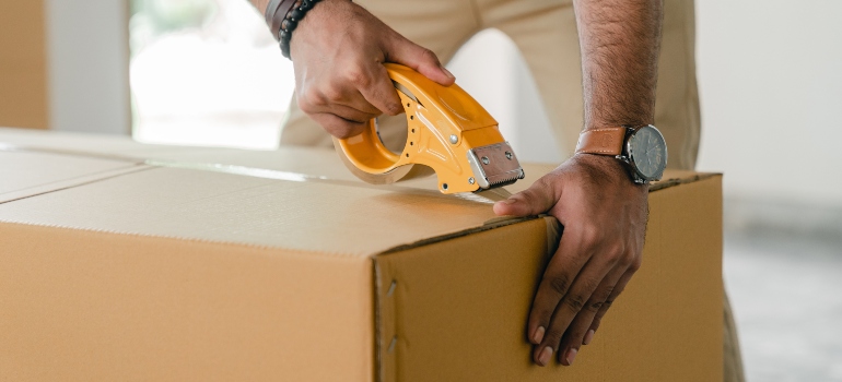 a man sealing cardboard box