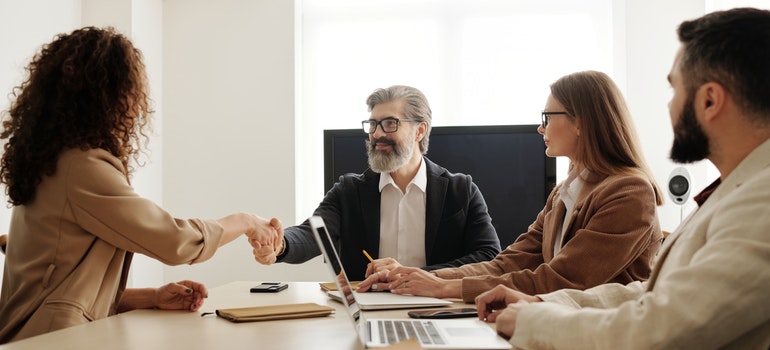 A man and a woman shaking hands in a meeting.