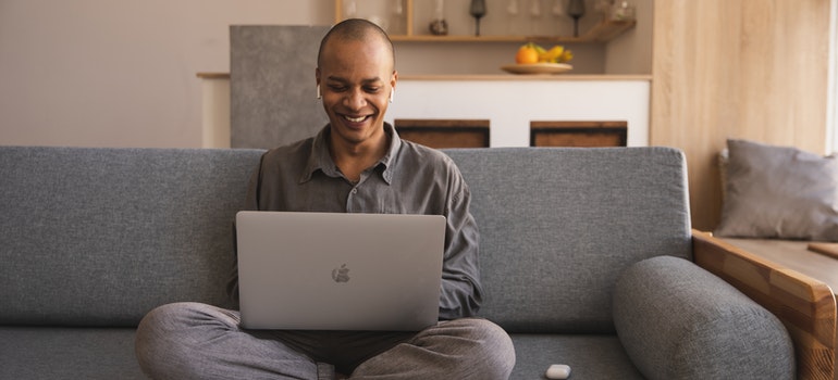 A happy person on the couch using a laptop.