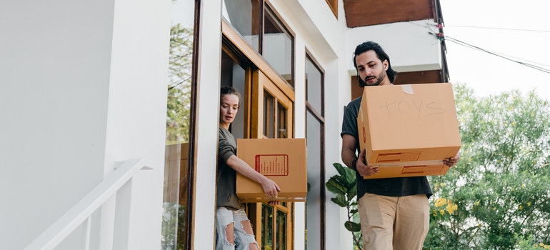 Two people carrying carton boxes.