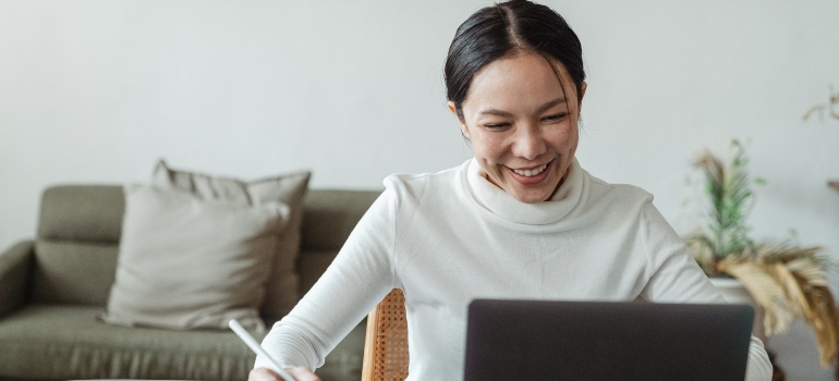 A woman smiling while looking at her laptop.