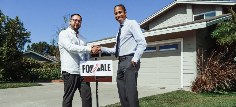 Two men shaking hands over the sign that says 